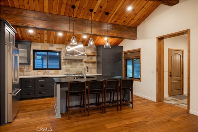 kitchen with a kitchen island with sink, decorative light fixtures, high end refrigerator, and decorative backsplash