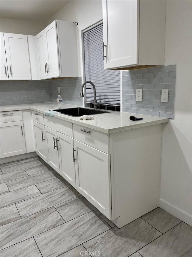 kitchen with sink, light stone countertops, and white cabinets