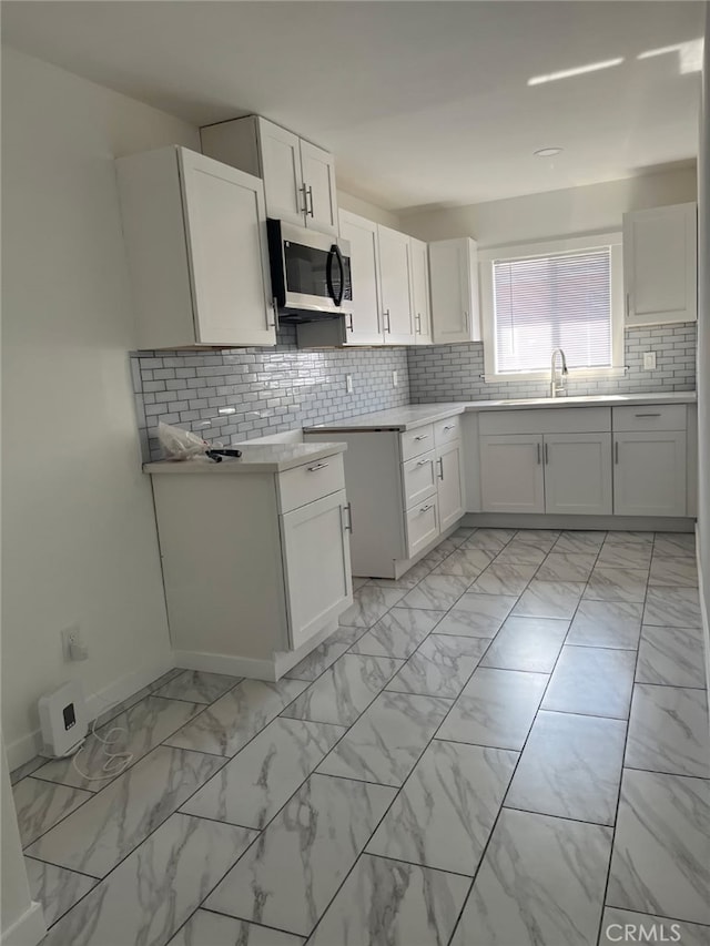 kitchen featuring sink, decorative backsplash, and white cabinets