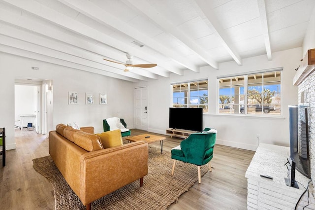 living room with ceiling fan, beam ceiling, hardwood / wood-style floors, and a brick fireplace