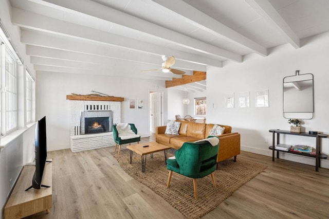 living room featuring light hardwood / wood-style flooring, beam ceiling, a fireplace, and ceiling fan