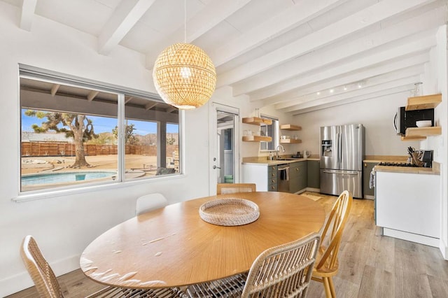 dining room featuring a healthy amount of sunlight, sink, a chandelier, and light hardwood / wood-style flooring