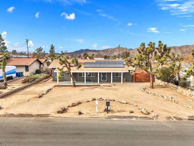 single story home with a mountain view and solar panels