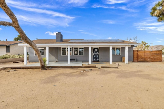 rear view of property with a porch and solar panels