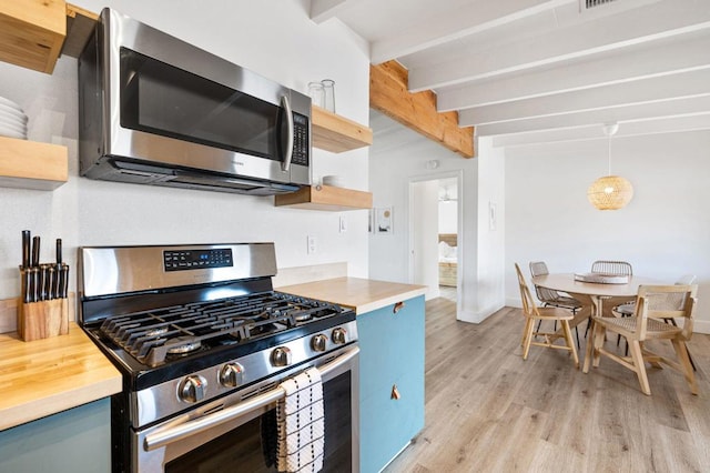 kitchen with beamed ceiling, appliances with stainless steel finishes, blue cabinets, and light wood-type flooring