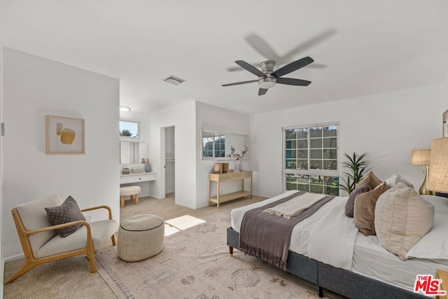 bedroom with ceiling fan, ensuite bathroom, and light colored carpet