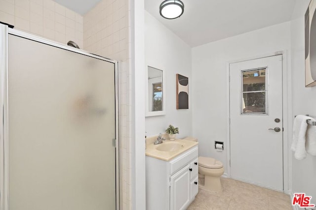 bathroom with a shower with door, vanity, tile patterned flooring, and toilet