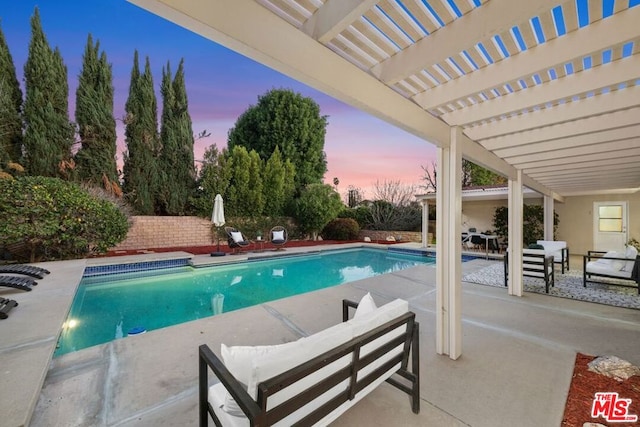 pool at dusk with a pergola, an outdoor hangout area, and a patio area