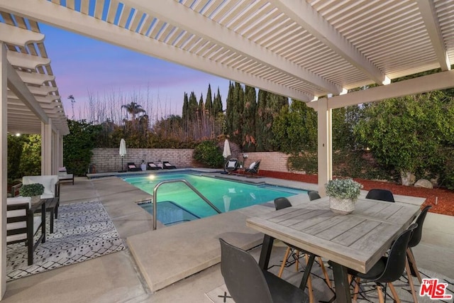 pool at dusk featuring a pergola and a patio area