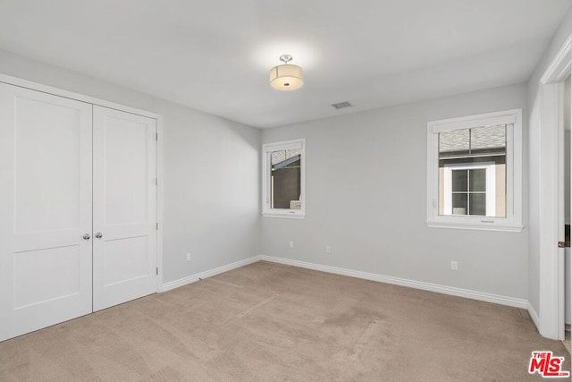 unfurnished bedroom with light carpet and a closet