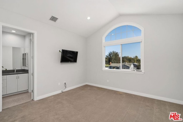 interior space with vaulted ceiling, sink, and light colored carpet