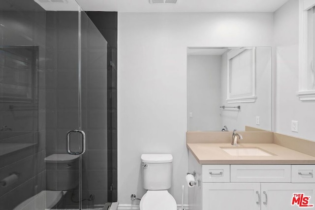 bathroom featuring vanity, toilet, and a shower with door