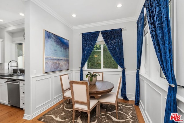 dining room with ornamental molding, light hardwood / wood-style floors, and sink