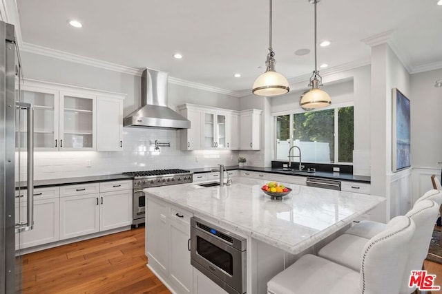 kitchen with white cabinetry, appliances with stainless steel finishes, sink, and wall chimney exhaust hood