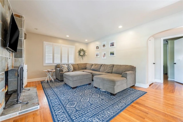 living room with a tiled fireplace and hardwood / wood-style flooring