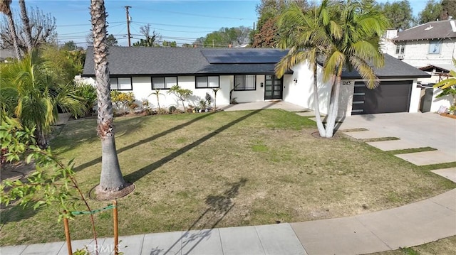 view of front of home with a garage, a front lawn, and solar panels