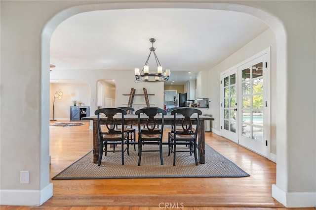 dining room featuring french doors, wood-type flooring, and a chandelier