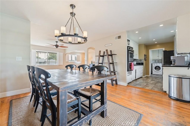 dining room with washer / dryer, ceiling fan with notable chandelier, and light wood-type flooring