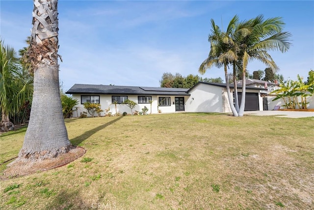 single story home with a garage, a front yard, and solar panels