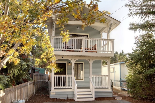 rear view of property with a porch and a balcony