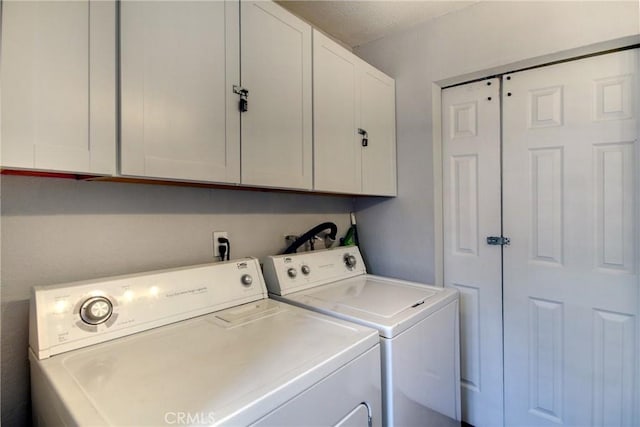 washroom with cabinets, washer and dryer, and a textured ceiling