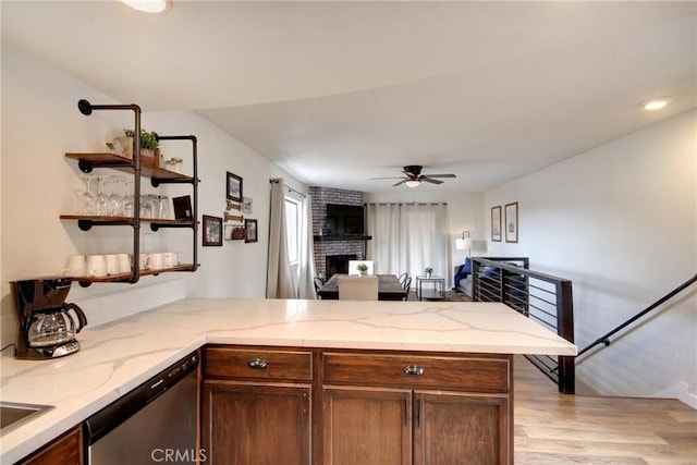 kitchen with kitchen peninsula, a fireplace, dishwasher, light hardwood / wood-style floors, and ceiling fan