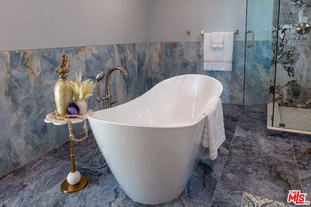 bathroom featuring a washtub and tile walls