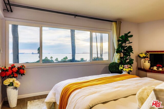 bedroom with a water view and hardwood / wood-style floors