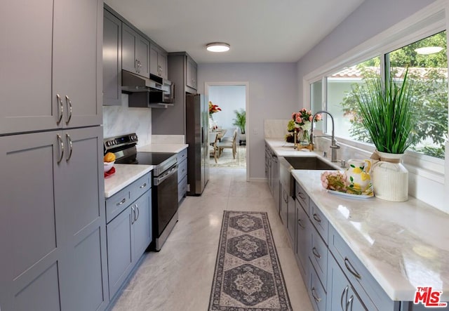 kitchen featuring sink, light stone counters, light tile patterned floors, gray cabinets, and stainless steel appliances