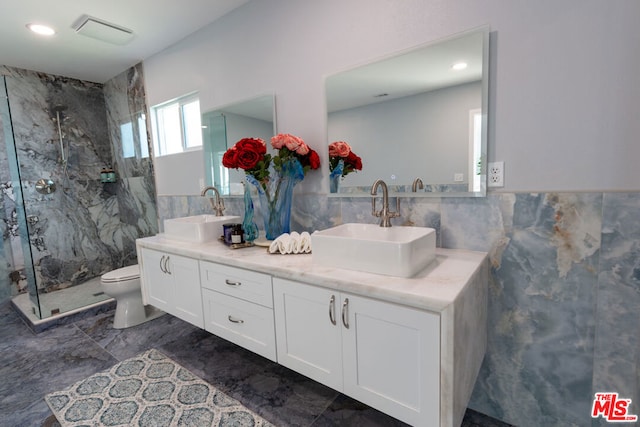 bathroom with tile walls, vanity, toilet, and tiled shower