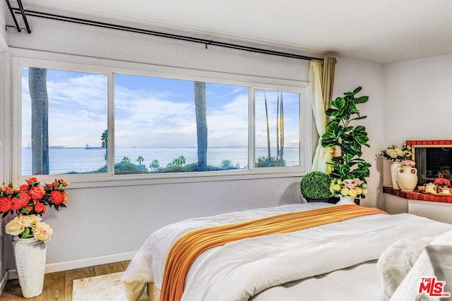 bedroom featuring multiple windows, wood-type flooring, and a water view