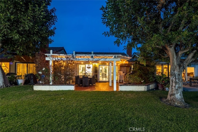 back house at night with a patio and a yard