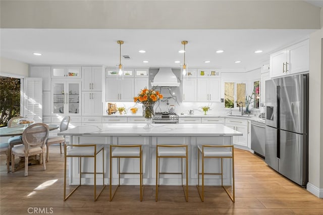 kitchen with a kitchen island, premium range hood, and appliances with stainless steel finishes