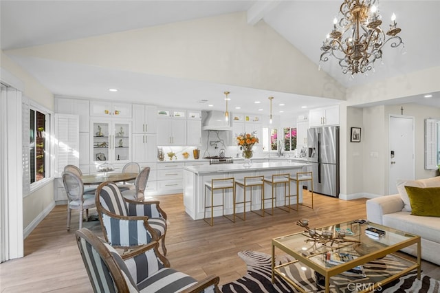 living room with a notable chandelier, high vaulted ceiling, beamed ceiling, and light wood-type flooring