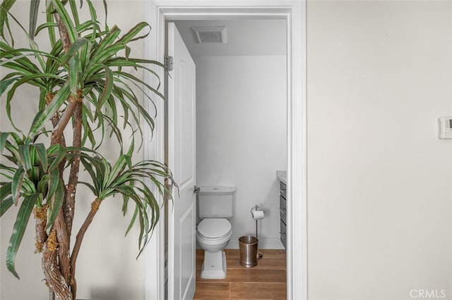 bathroom with hardwood / wood-style flooring, vanity, and toilet