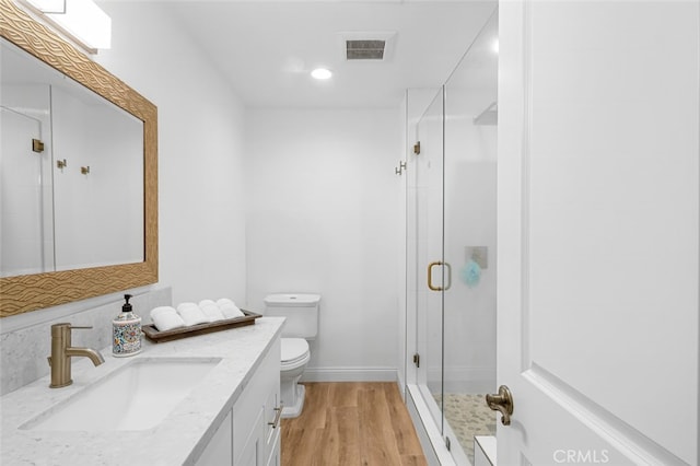 bathroom with wood-type flooring, vanity, an enclosed shower, and toilet