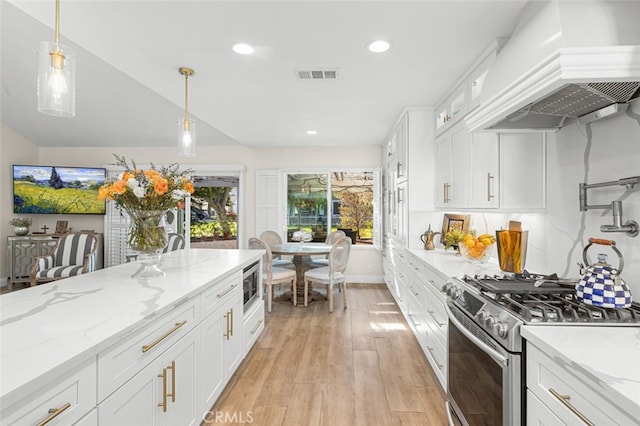 kitchen featuring white cabinetry, stainless steel appliances, light stone counters, decorative light fixtures, and custom exhaust hood