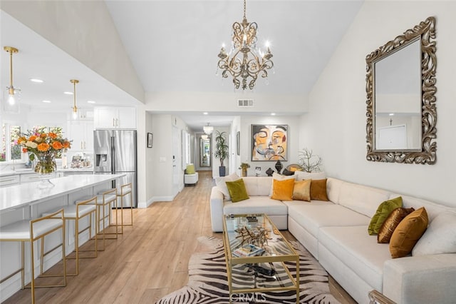 living room with vaulted ceiling, light hardwood / wood-style floors, and a chandelier