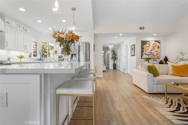 kitchen featuring white cabinetry, pendant lighting, light hardwood / wood-style floors, and a breakfast bar