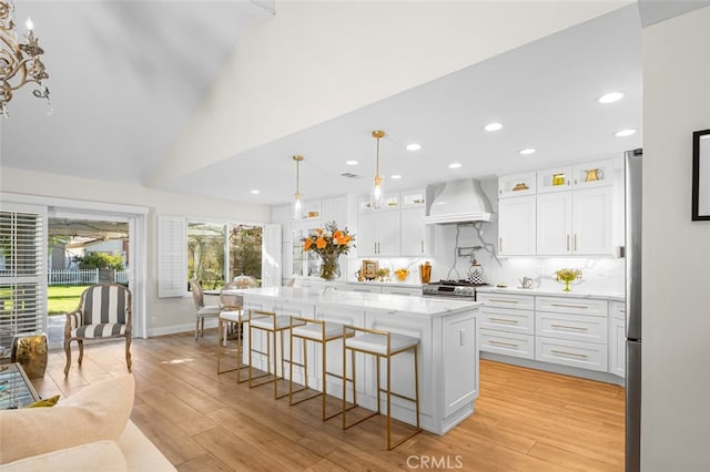 kitchen with white cabinetry, premium range hood, a center island, and decorative light fixtures