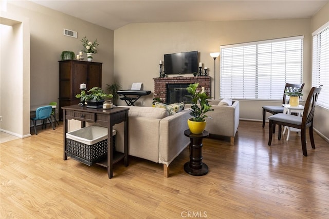 living room with lofted ceiling, a fireplace, and light hardwood / wood-style flooring