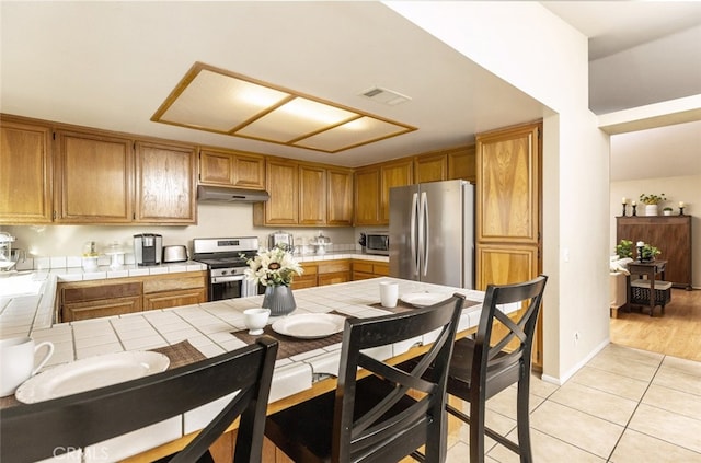 kitchen featuring appliances with stainless steel finishes, tile countertops, and light tile patterned floors