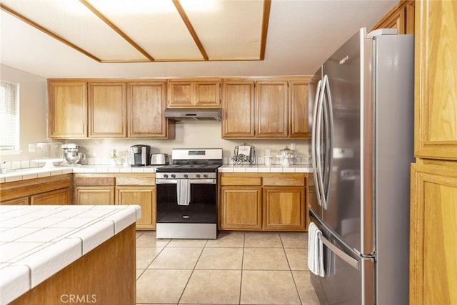 kitchen with light tile patterned floors, tile counters, and appliances with stainless steel finishes