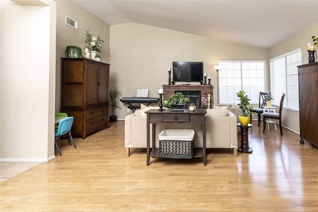 living room with lofted ceiling, a fireplace, and light hardwood / wood-style flooring