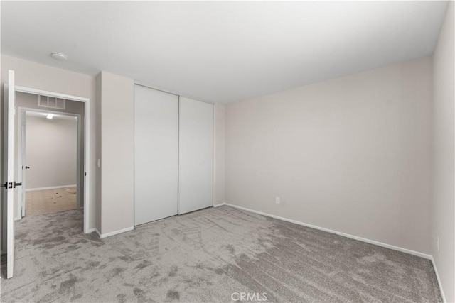 unfurnished bedroom featuring light carpet and a closet