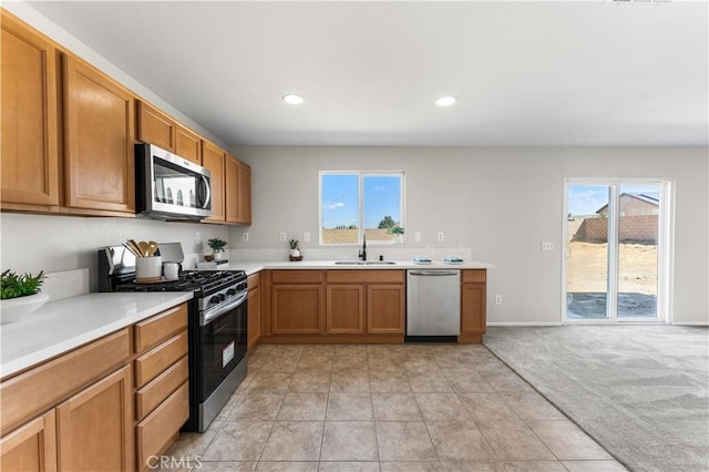 kitchen featuring stainless steel appliances, sink, and light carpet