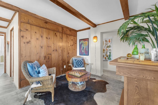 living area featuring beamed ceiling and wood walls