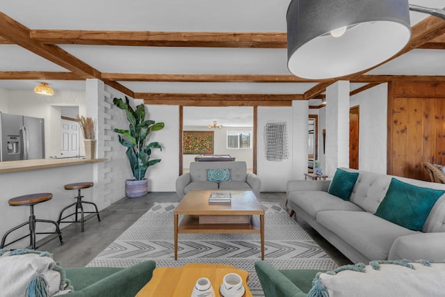 living room featuring an inviting chandelier, beam ceiling, and concrete flooring