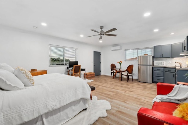 bedroom featuring multiple windows, stainless steel fridge, a wall unit AC, and ceiling fan