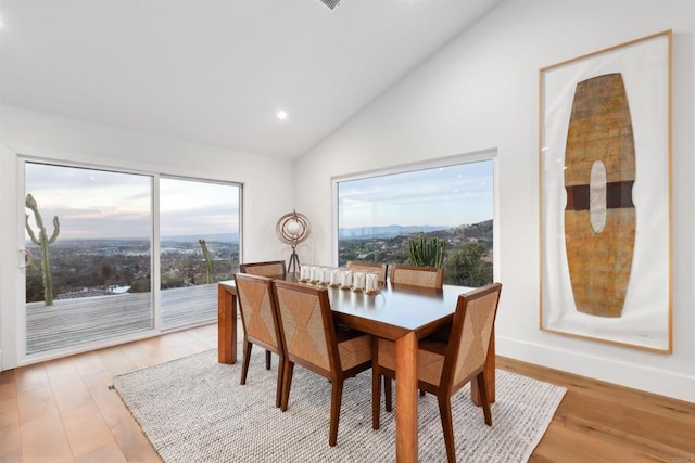 dining area featuring a mountain view, light hardwood / wood-style flooring, and vaulted ceiling